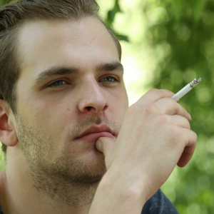 charming-young-guy-smoking-a-cigarette-relax-looking-out-spring-season-day-view_htopulfex_thumbnail-full01