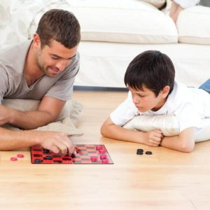 handsome-man-playing-checkers-with-his-son-lying-on-the-floor
